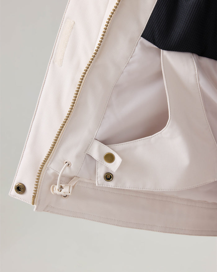 Close-up of the inside of the Roxy Billie Jacket, a women’s snow jacket, highlighting a pocket, a zipper, snap buttons, and a drawstring detail with durable microripstop protection.