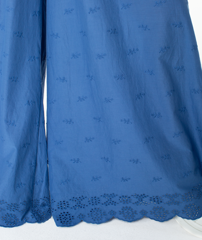 Introducing the Cambria Pant by Roxy: Featuring blue fabric adorned with embroidered floral patterns and a scalloped, cut-out lace hem, this lightweight material drapes softly—ideal for relaxed tailoring or pairing with flowy pieces to create a vibrant statement ensemble.