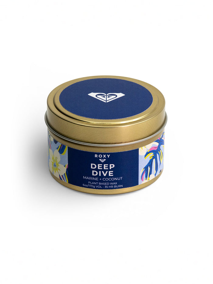 The Roxy Deep Dive Palm Tin Candle features creamy coconut notes in plant-based wax, a refreshing marine breeze, and up to 45 hours of burn time in a gold tin with a blue lid and floral design.