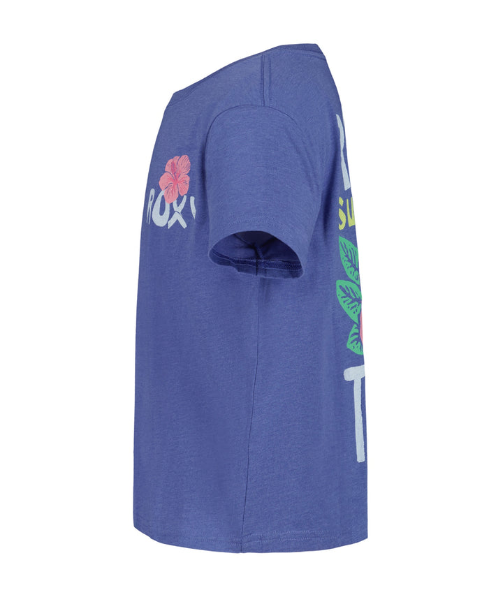 A side-view of the Girls' Surf Trip Tee by Roxy—a blue cotton short-sleeve shirt with partial floral graphics and white, pink, and green printed text on front and back.