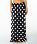 A person wearing the Roxy Iyla Skirt in Anthracite Soft Dot—a long black skirt featuring bold white polka dots and a tie waist drawstring. The image captures the skirt from lower torso to feet against a white background, making it ideal for styling solo or as part of a matching set.