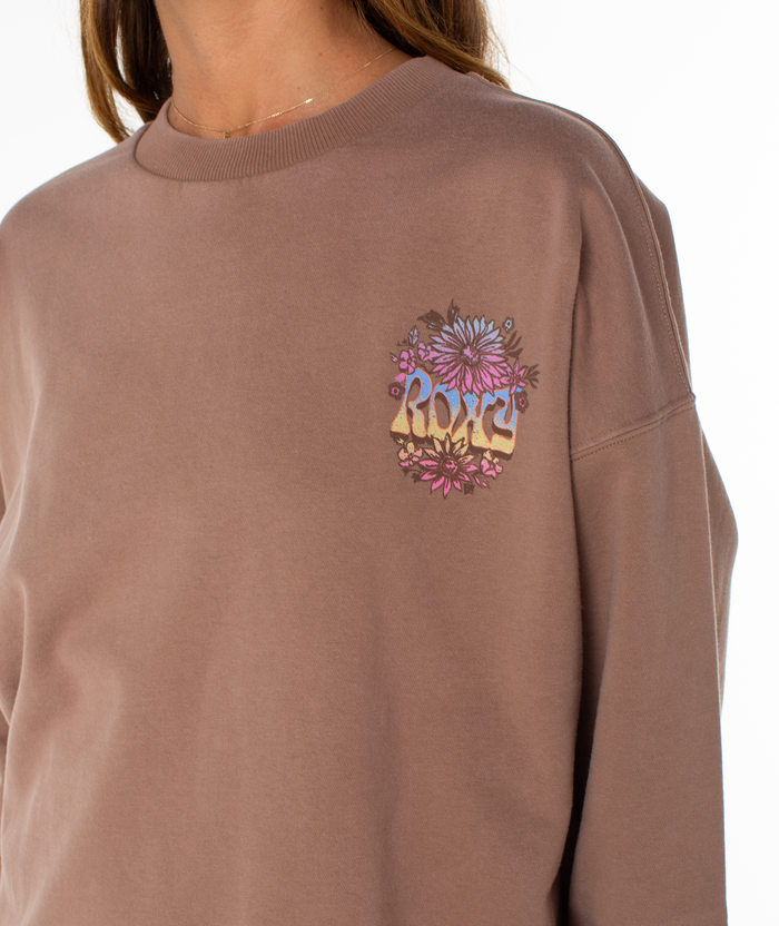 A person wearing the Roxy Lineup Oversized Crew, a mauve sweatshirt with a small floral graphic and "ROXY" on the left chest. The image crops to show only their upper torso and neck.