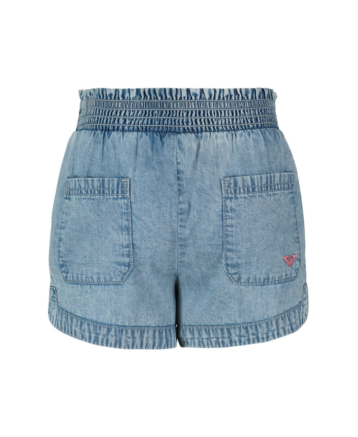 The Roxy Little Girls' Soleil Short features lightweight light blue denim, a smocked elastic waistband, two back pockets, and a small pink logo on the lower right pocket. The shorts are shown against a white background.
