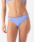A woman wears the Roxy Loop Me In Hipster Full Bikini Bottom in Cornflower with black stitching and a ribbed texture, shown from midriff to upper thighs against a plain white background.