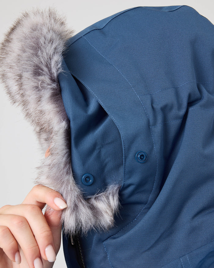 A person holds the faux fur-trimmed hood of a blue Meade Jacket from Roxy, partially covering their face.