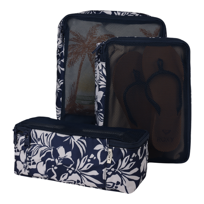 A set of three navy blue Roxy Packing Cubes adorned with white floral patterns and mesh fronts. Made from lightweight ripstop fabric, these travel essentials are perfect for organizing your luggage—one cube contains brown flip-flops, while another displays a palm tree print interior.