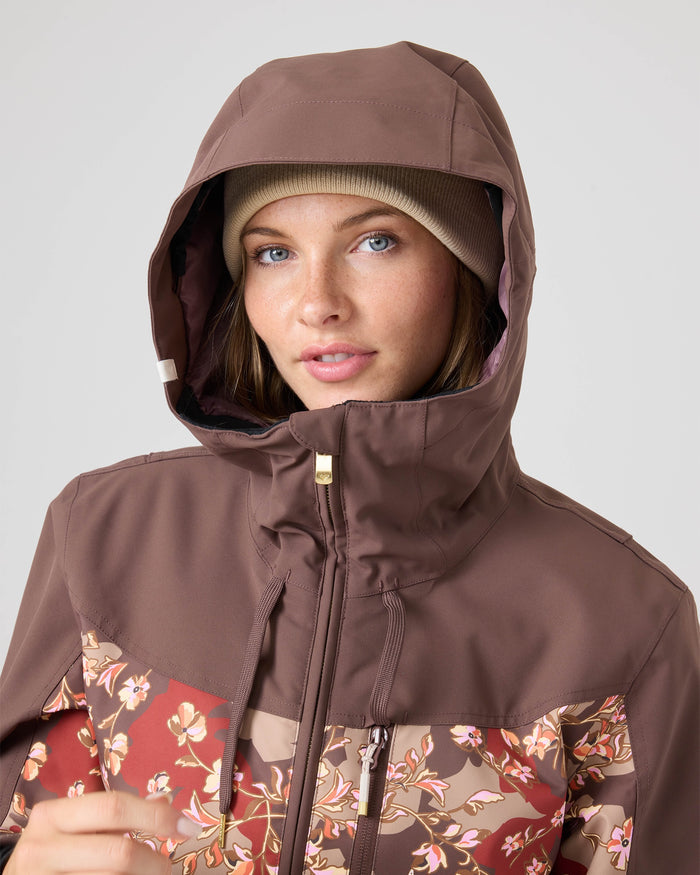 A person wearing the Roxy Presence Parka Jacket with a floral pattern and a beige beanie, looking at the camera against a plain background.