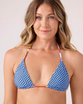 A woman with long, wavy blonde hair smiles softly wearing the Roxy Ripple Effect Reversible Mini Tiki Triangle Bikini Top in Blue Multi. The adjustable tie straps stand out against a plain, light background.