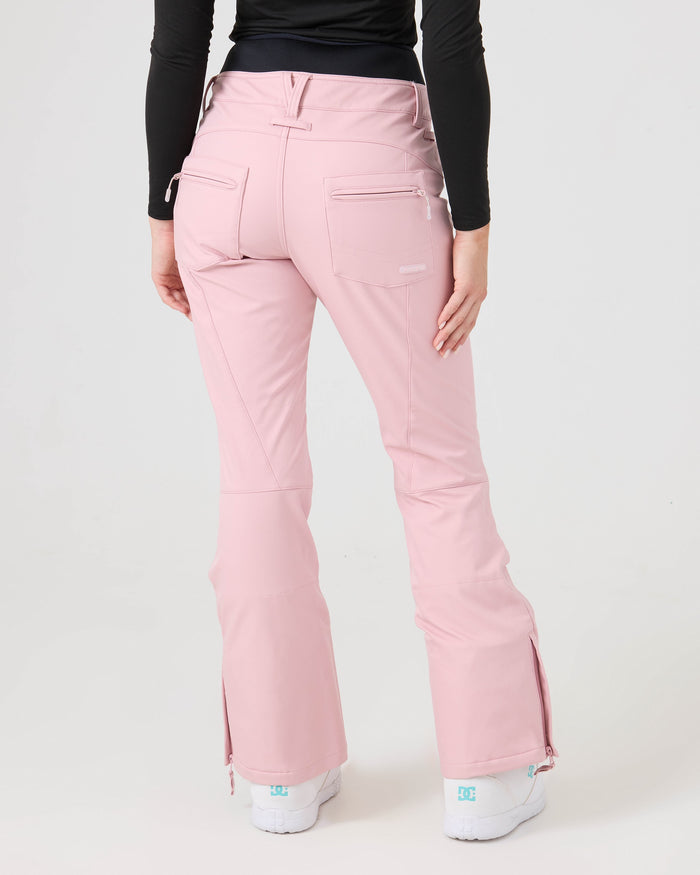 A person wearing the Roxy Rising High Short Pants in light pink, styled with a black long-sleeve top and white sneakers, stands facing away from the camera against a plain white background.