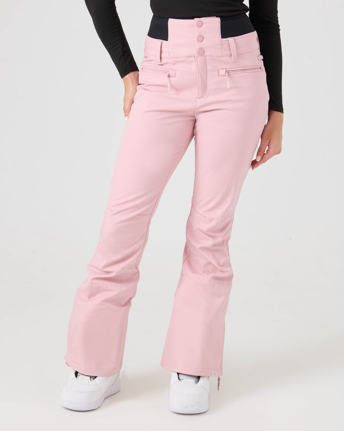 A person is shown from the waist down, standing against a plain white background, wearing the Roxy Rising High Short Pants in light pink recycled fabric, paired with a black long-sleeve top and white shoes.
