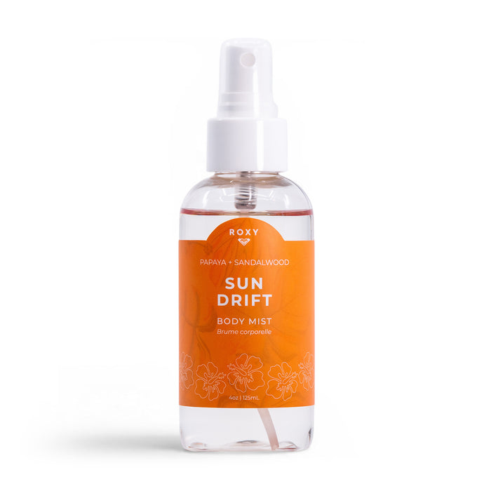 A clear spray bottle labeled Roxy Sun Drift Body Mist, featuring papaya, guava, and sandalwood scent with an orange label and white floral designs, is shown on a white background.