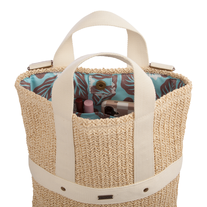The Sunny Stash Backpack by Roxy features woven straw construction with cream handles and opens to reveal a blue patterned lining and multiple cosmetic items inside—delivering the perfect balance of charm and functionality for anyone looking for a stylish or versatile beach backpack.